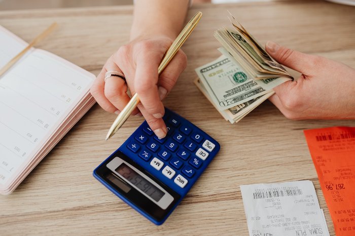 Person counting money with a calculator